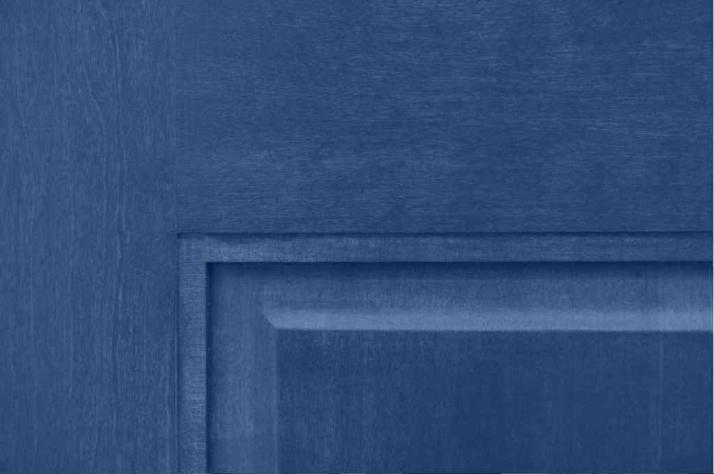 Up-close view of a wood that is stained blue. The wood grain of an interior pine door is still visible under a blue stain.