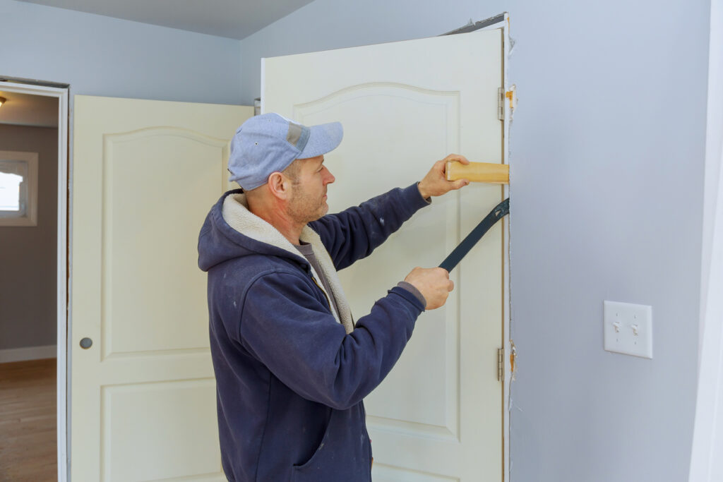 A handyman inserting shims in the frame of an interior door