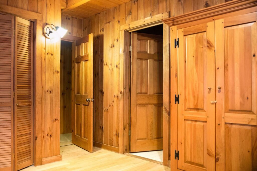 A corner of a rustic cabin featuring pine doors and walls.