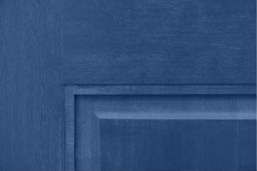 Up-close view of a wood that is stained blue. The wood grain of an interior pine door is still visible under a blue stain.