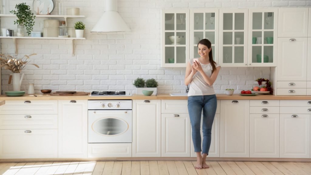 A happy woman looking at her smartphone in a spacious kitchen