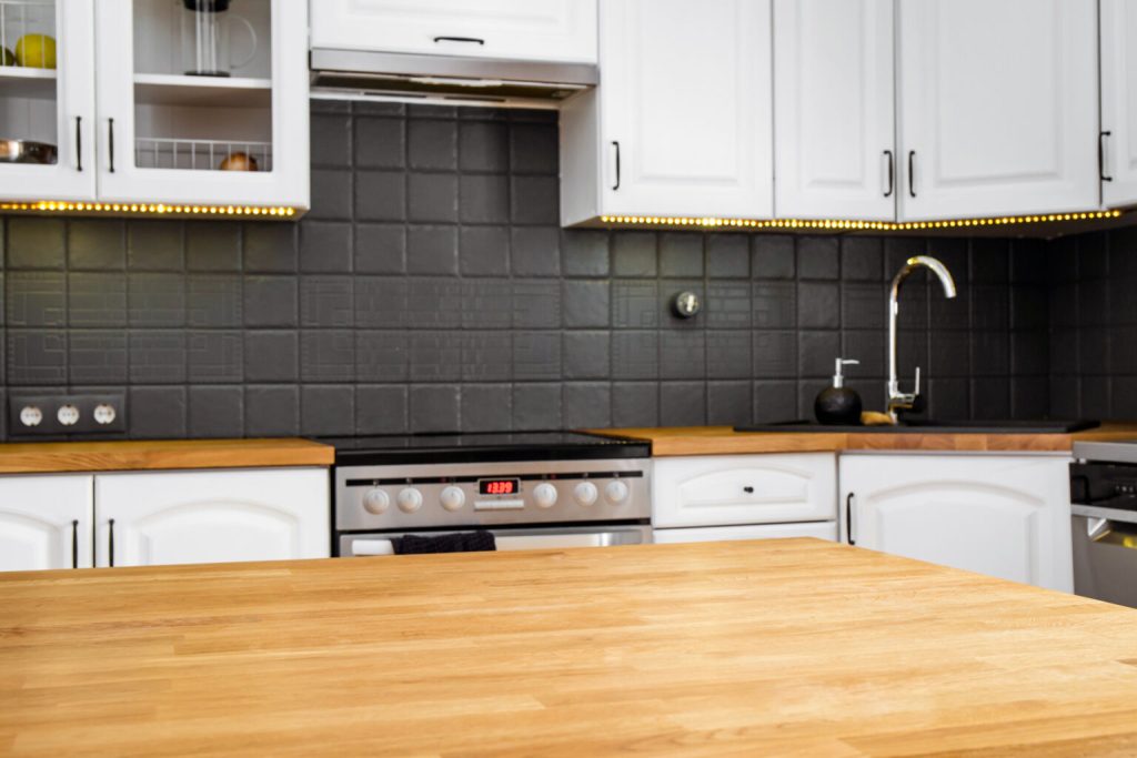 A kitchen with black tiles and a wooden butcher block countertop