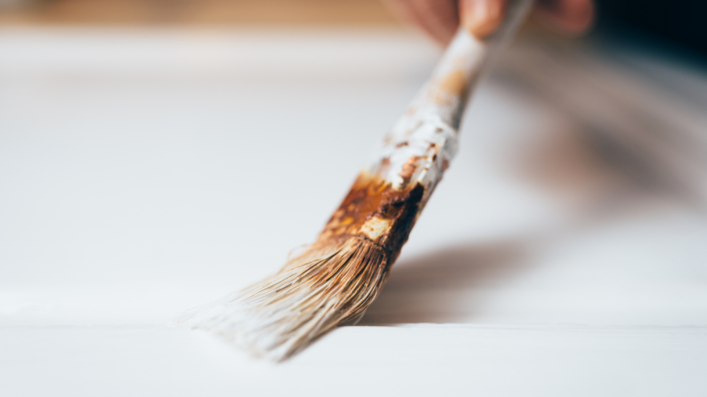 A person painting a door with a white paint