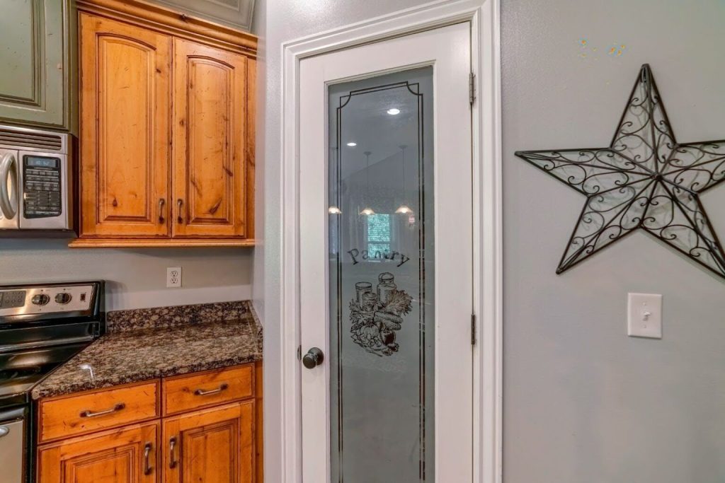 A kitchen with wooden cabinets and a pantry with a stained-glass door